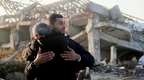 Reuters Palestinians returning to their homes hug in front of the remains of a building in Gaza City (27/01/25)