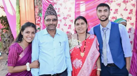 Family handout The Joshi family stands in a row smiling at the camera, with several coloured sheets as a backdrop