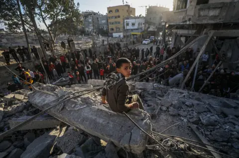 EPA A Palestinian boy sits on rubble following Israeli airstrikes on Al Nuseirat refugee camp, central Gaza