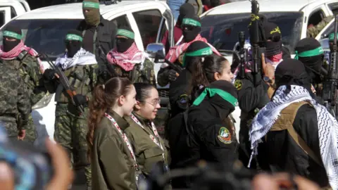 Reuters Israeli hostages Naama Levy, Liri Albag and Karina Ariev walk before being delivered to the representative of the International Committee of the Red Cross (ICRC) by Hamas militants, as they are released from the Gaza Strip