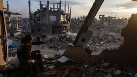 EPA Palestinian children watch the sunset from the destroyed house in Jabalia refugee camp, north of Gaza City (11 February 2025)