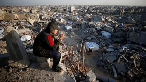 Reuters A boy looks at destroyed buildings in Jabalia refugee camp, northern Gaza (26 February 2025)