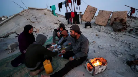 Reuters A Palestinian family break their fast during the Islamic holy month of Ramadan, on the rubble of their house in Jabalia refugee camp, northern Gaza (2 March 2025)