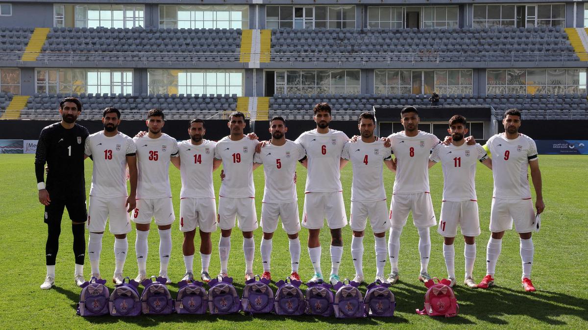 Iran’s football players hold schoolbags wearing black armbands in solidarity with slain girls